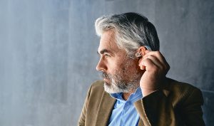 Distinguished man using an over-the-counter hearing aid