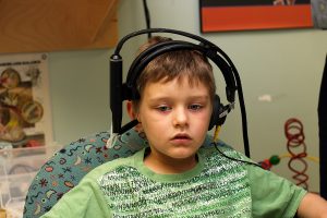 Young boy wearing headphones while having his hearing tested at a speech and hearing center