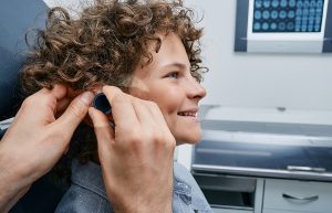 Pediatric audiology doctor testing a curly-haired child's hearing