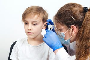 Pediatric audiology doctor examining a young boy's ear