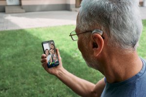 Senior man wearing a hearing aid and holding a smartphone