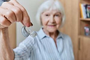 Smiling older woman holding a hearing aid