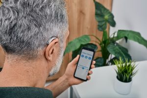 Man using smartphone app to adjust his hearing aid settings